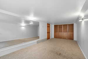 Unfurnished bedroom featuring carpet, a baseboard heating unit, and a closet