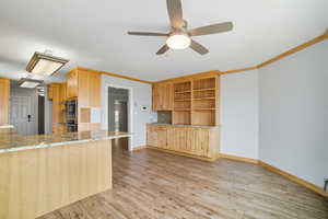 Kitchen featuring light wood finished floors, light brown cabinets, light stone countertops, a peninsula, and backsplash