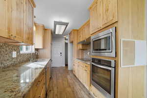 Kitchen featuring light brown cabinetry, appliances with stainless steel finishes, and light stone countertops