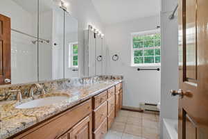 Full bathroom with double vanity, a baseboard radiator, light tile patterned flooring, and a bath