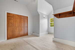 Additional living space featuring lofted ceiling, light colored carpet, and a baseboard radiator