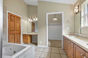 Full bathroom featuring double vanity, light tile patterned flooring, a tub with jets, and a spacious closet