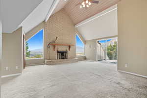 Unfurnished living room with a fireplace, carpet, high vaulted ceiling, ceiling fan, and healthy amount of natural light