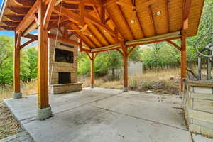 View of patio featuring an outdoor stone fireplace and an outdoor structure