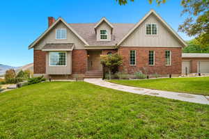 View of front of house featuring brick siding, a front lawn, a chimney, and roof with shingles