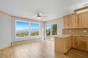 Kitchen featuring a baseboard heating unit, a mountain view, tasteful backsplash, light stone counters, and light wood-style floors