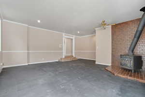 Unfurnished living room with a wood stove, crown molding, ceiling fan, and recessed lighting