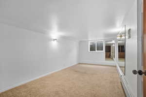 Carpeted spare room featuring a baseboard radiator and a textured ceiling