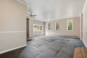 Empty room featuring crown molding, healthy amount of natural light, a baseboard heating unit, and a ceiling fan