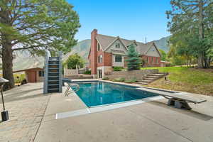 View of swimming pool with stairway, a patio, a mountain view, and a diving board