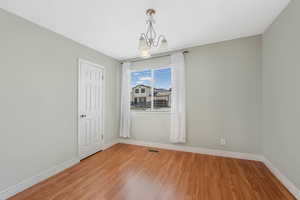 Spare room featuring light wood-style flooring and a chandelier