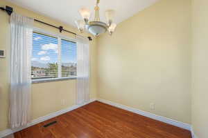 Spare room with wood finished floors and a chandelier