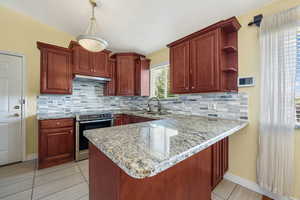 Kitchen featuring electric stove, light stone countertops, light tile patterned floors, and decorative backsplash
