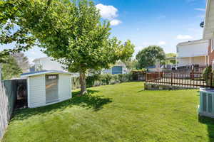 Fenced backyard featuring a shed