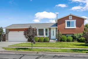 View of front of property with brick siding, a front yard, concrete driveway, and a garage