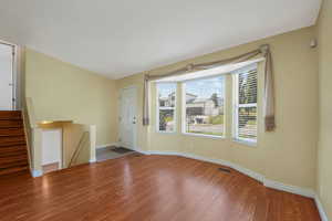 Unfurnished living room with wood finished floors and stairway