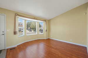 Empty room with wood finished floors and lofted ceiling