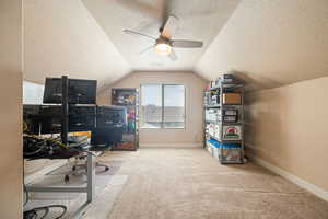 Carpeted office featuring a textured ceiling, lofted ceiling, and ceiling fan
