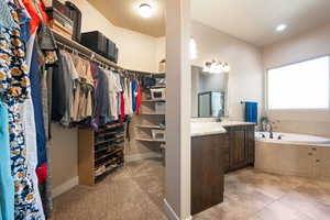 Full bath with vanity, a shower stall, a garden tub, a walk in closet, and light tile patterned floors
