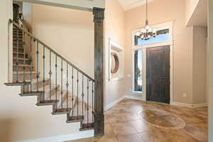 Entrance foyer with light tile patterned floors, a chandelier, and a high ceiling