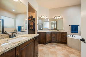 Bathroom with two vanities, a bath, a spacious closet, and light tile patterned floors