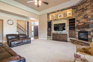 Living area featuring built in features, stairway, a ceiling fan, carpet, and a chandelier