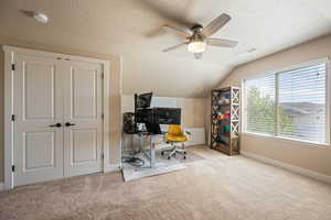 Office area featuring carpet floors, vaulted ceiling, a ceiling fan, and a textured ceiling