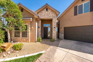 View of front of home featuring stone siding, concrete driveway, stucco siding, and an attached garage