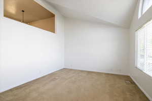 Carpeted empty room with high vaulted ceiling