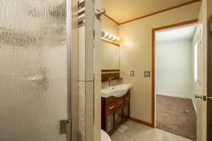 Bathroom featuring vanity, crown molding, a stall shower, and light tile patterned floors