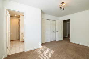Unfurnished bedroom featuring light colored carpet, a closet, light tile patterned floors, and ornamental molding