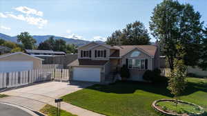 Split level home with brick siding, concrete driveway, an attached garage, a mountain view, and a chimney