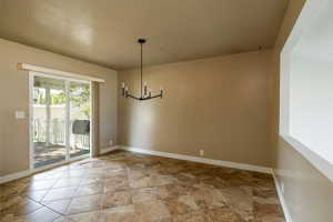 Unfurnished dining area featuring a chandelier and a textured ceiling