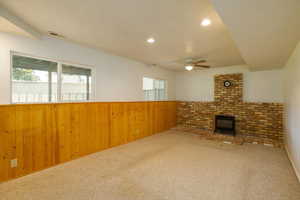Unfurnished living room with wainscoting, wood walls, carpet floors, recessed lighting, and a wood stove