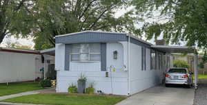 Attached carport, concrete driveway, and a front lawn
