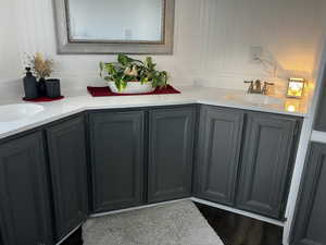 Full bathroom with double vanity and dark wood-type flooring