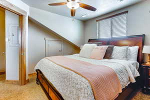Carpeted bedroom with ceiling fan, electric panel, and a textured ceiling
