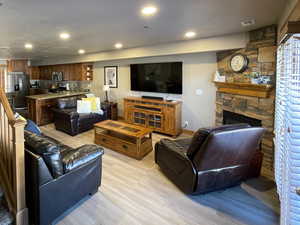 Living area with a fireplace, light wood finished floors, stairs, recessed lighting, and a textured ceiling