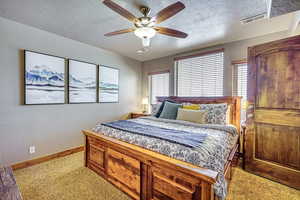 Bedroom with a textured ceiling, light colored carpet, and ceiling fan