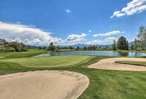 Surrounding community with a water and mountain view, golf course view, and a yard