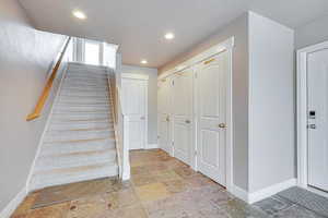 Stairway with recessed lighting and stone tile flooring