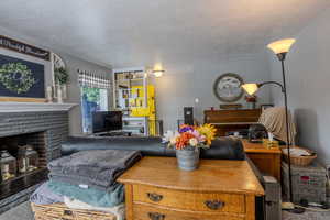 Carpeted living area featuring a textured ceiling and a stone fireplace
