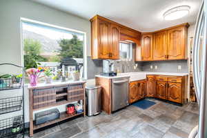 Kitchen with stainless steel appliances, backsplash, brown cabinetry, a mountain view, and dark stone finish floors