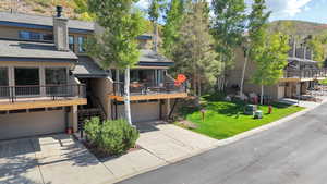 View of front of house with a deck with mountain view, driveway, an attached garage, a chimney, and a shingled roof