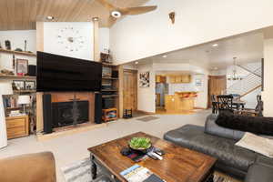 Living area featuring carpet, a chandelier, high vaulted ceiling, recessed lighting, and a brick fireplace