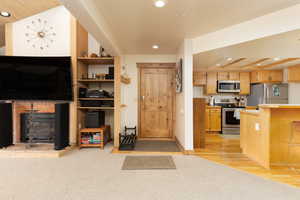 Kitchen featuring light countertops, stainless steel appliances, recessed lighting, light wood finished floors, and a brick fireplace