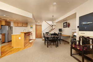 Dining room with light wood-style flooring, recessed lighting, a chandelier, light colored carpet, and stairs