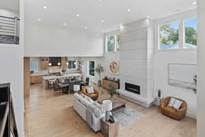 Living room with recessed lighting, a high ceiling, a fireplace, and light wood-style floors