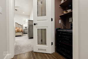 Walk in closet featuring dark wood-style floors, wine cooler, and dark colored carpet