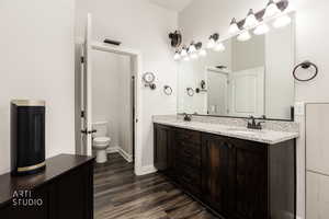 Bathroom with double vanity and dark wood-style flooring